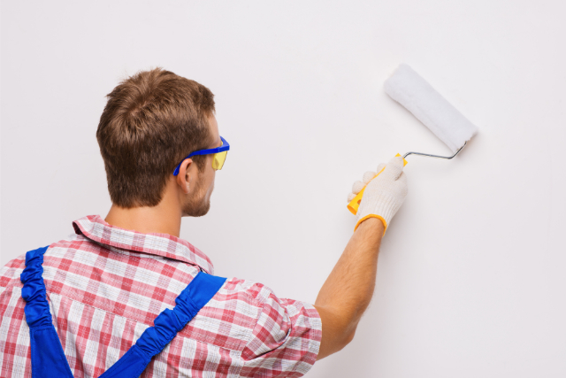 Experienced painter with roller and safety glasses on